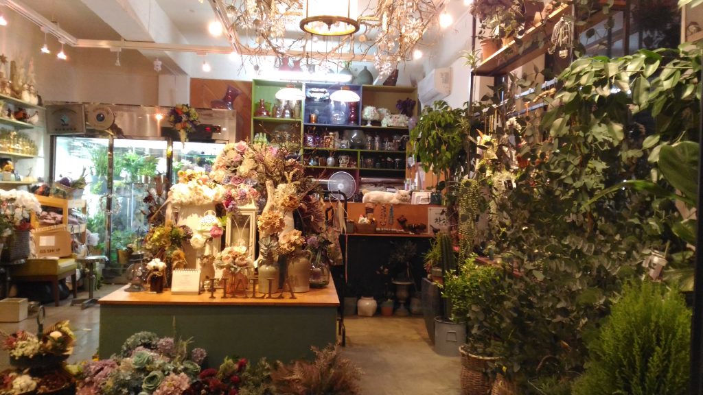 A flower shop in the market.  What else can you see?